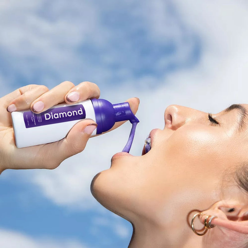 Kvinne med Diamond Smile lilla tannblekningsskum i hånden